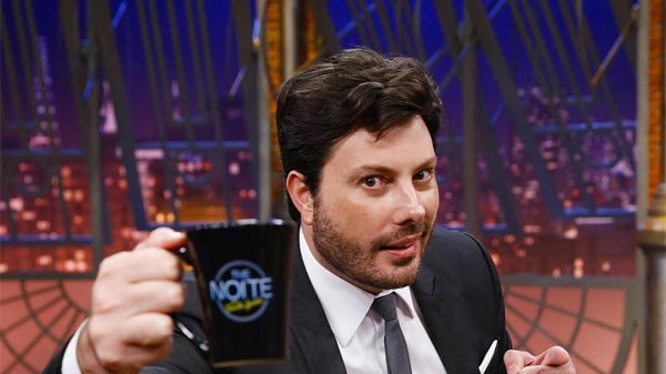 DANILO GENTILI, EM FOTO, MOSTRA A CANECA DE SEU PROGRAMA THE NOITE NO SBT