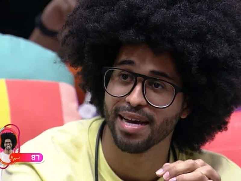 Luciano Estevam ao participar do BBB 22, usando uma camiseta amarela e cabelo back power.